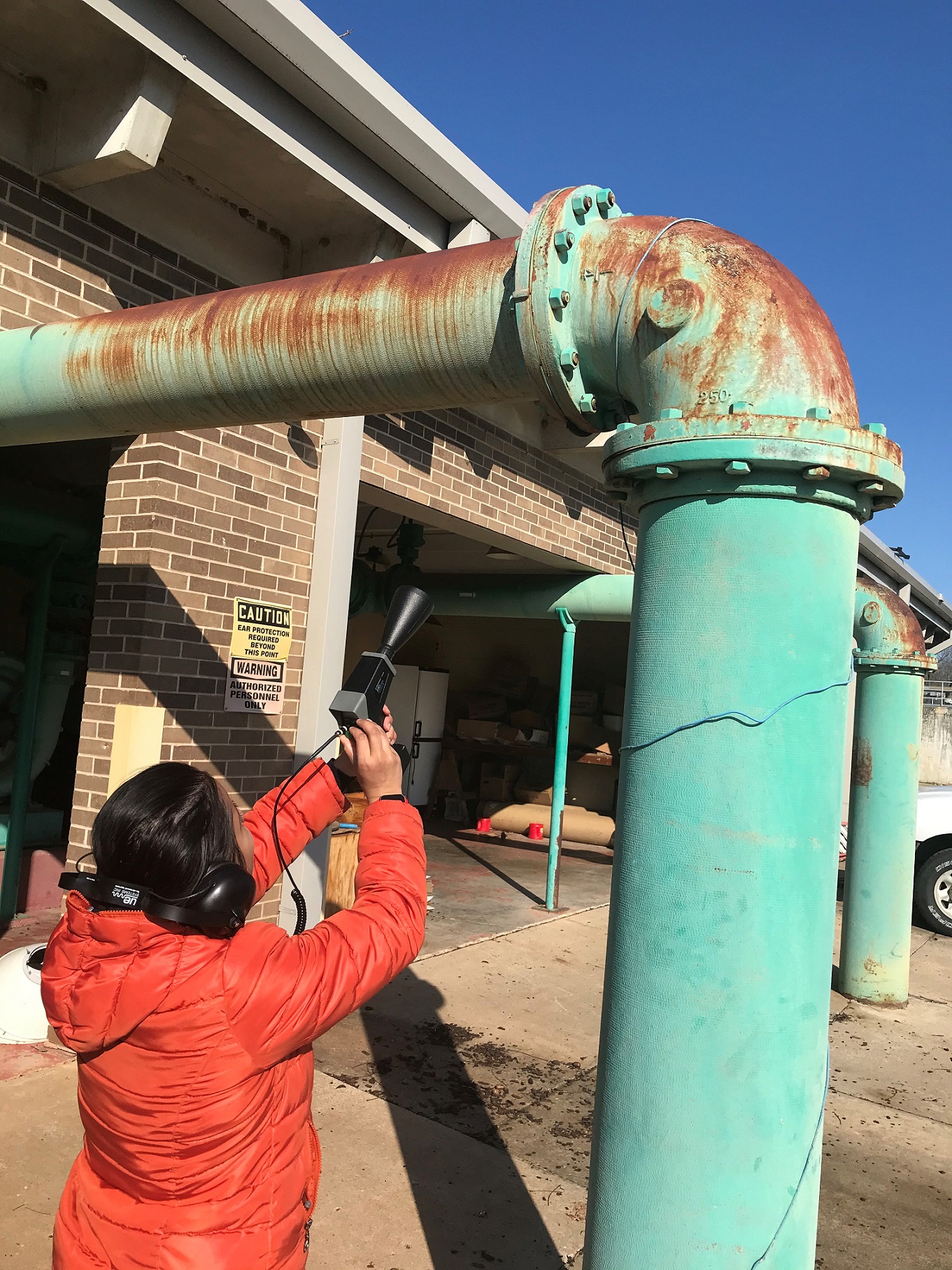 A student examines a pipe with some sort of device. A student examines a pipe with some sort of device.
